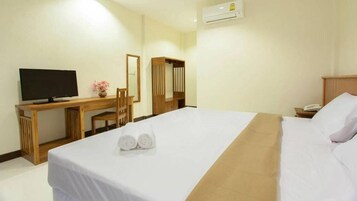 Une chambre d’hôtel comprenant un lit, un bureau avec une télévision, un miroir et une armoire.