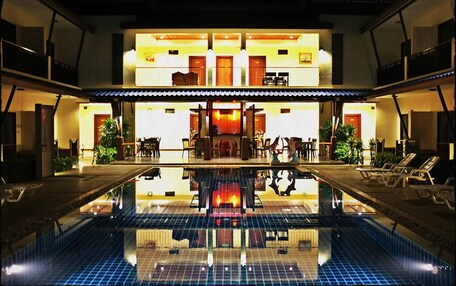 A hotel with a pool, a reception area, and a dining space.