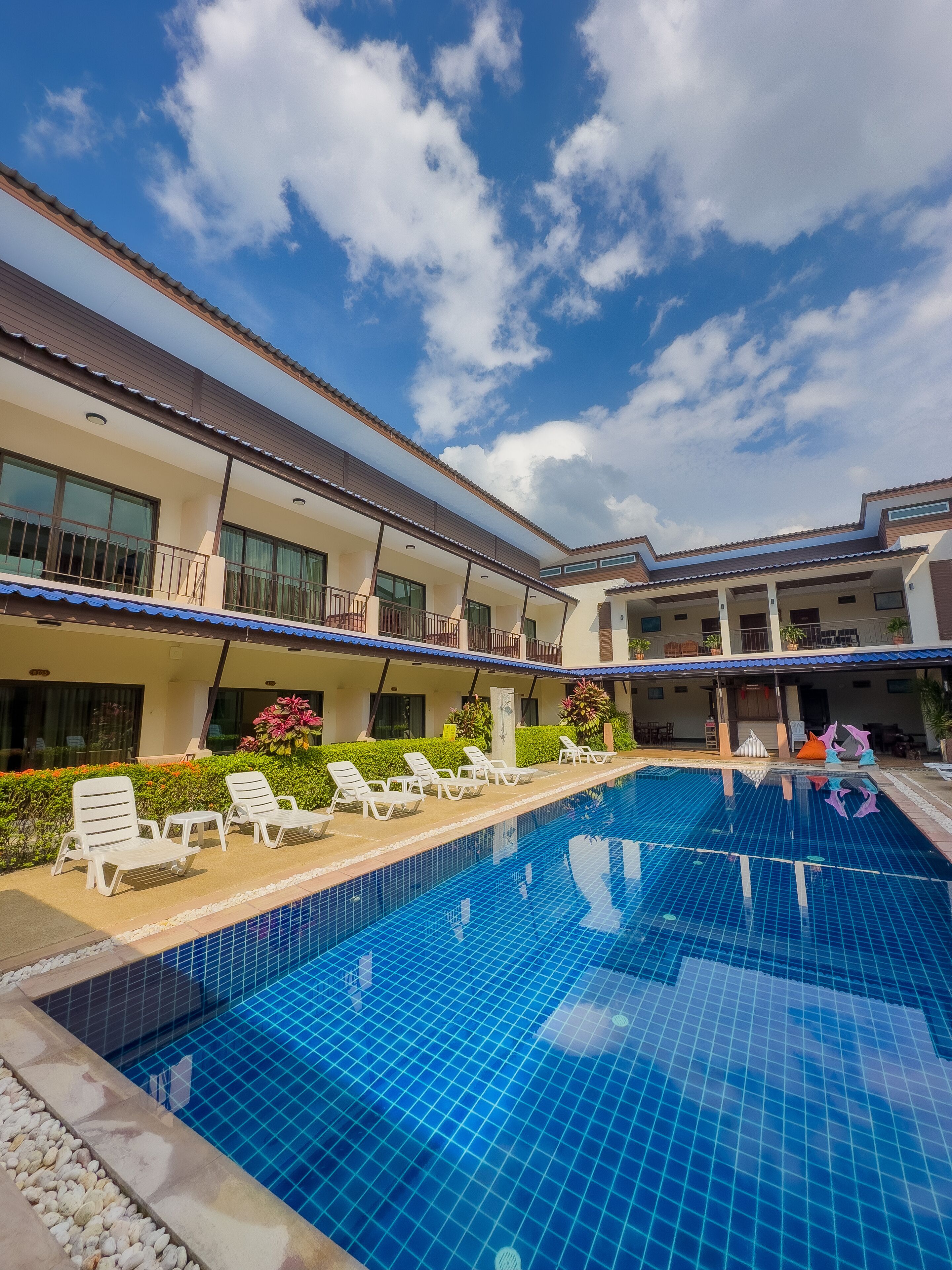 Una piscina con sillas de descanso y un edificio con balcones.