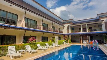 Una piscina con sillas de descanso y un edificio con balcones.