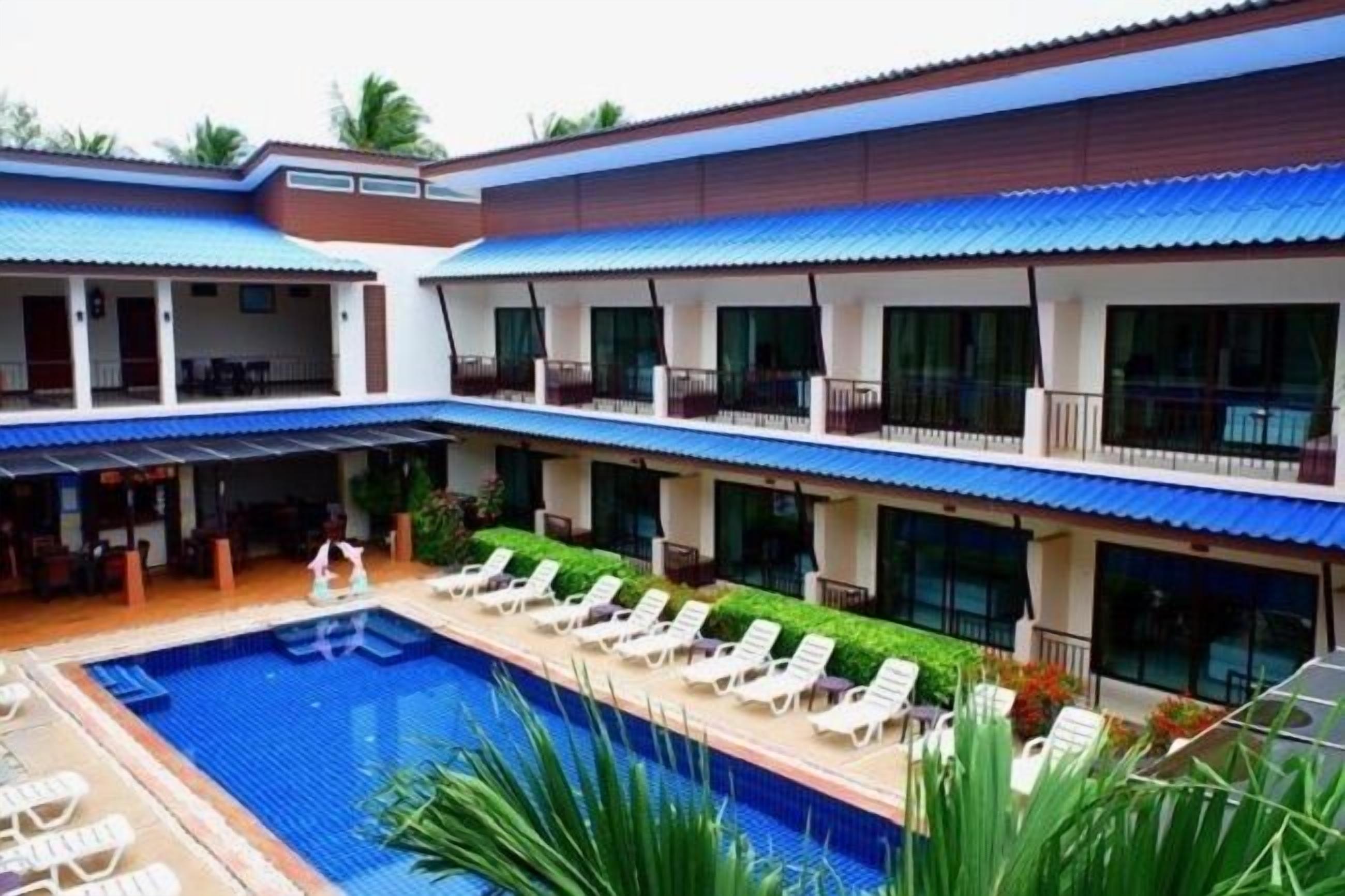 Un hotel con piscina, varios balcones y zonas de estar al aire libre.