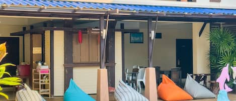 Un edificio de dos pisos con un patio cubierto, piscina y asientos al aire libre.