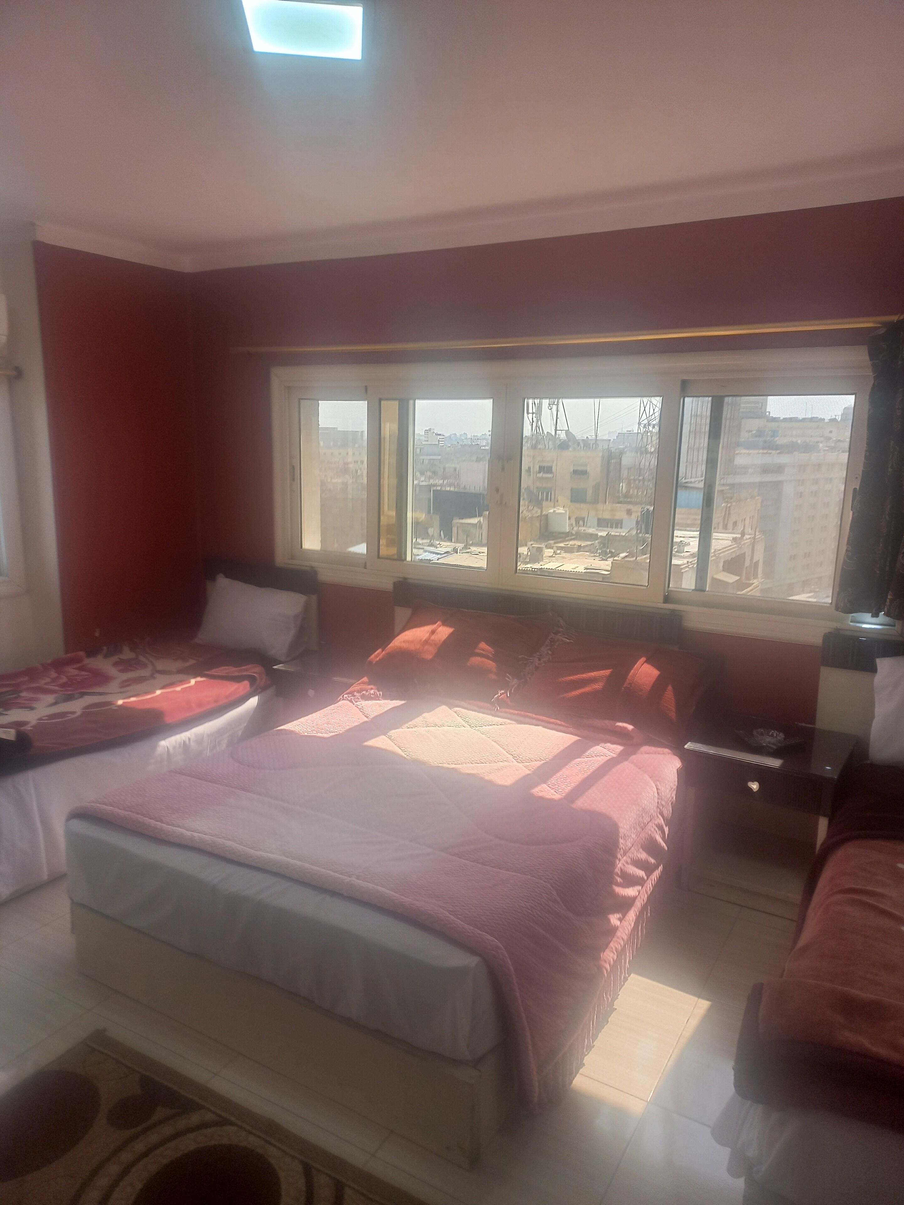 Een slaapkamer met een groot bed, een nachtkastje en een raam met uitzicht op gebouwen.
