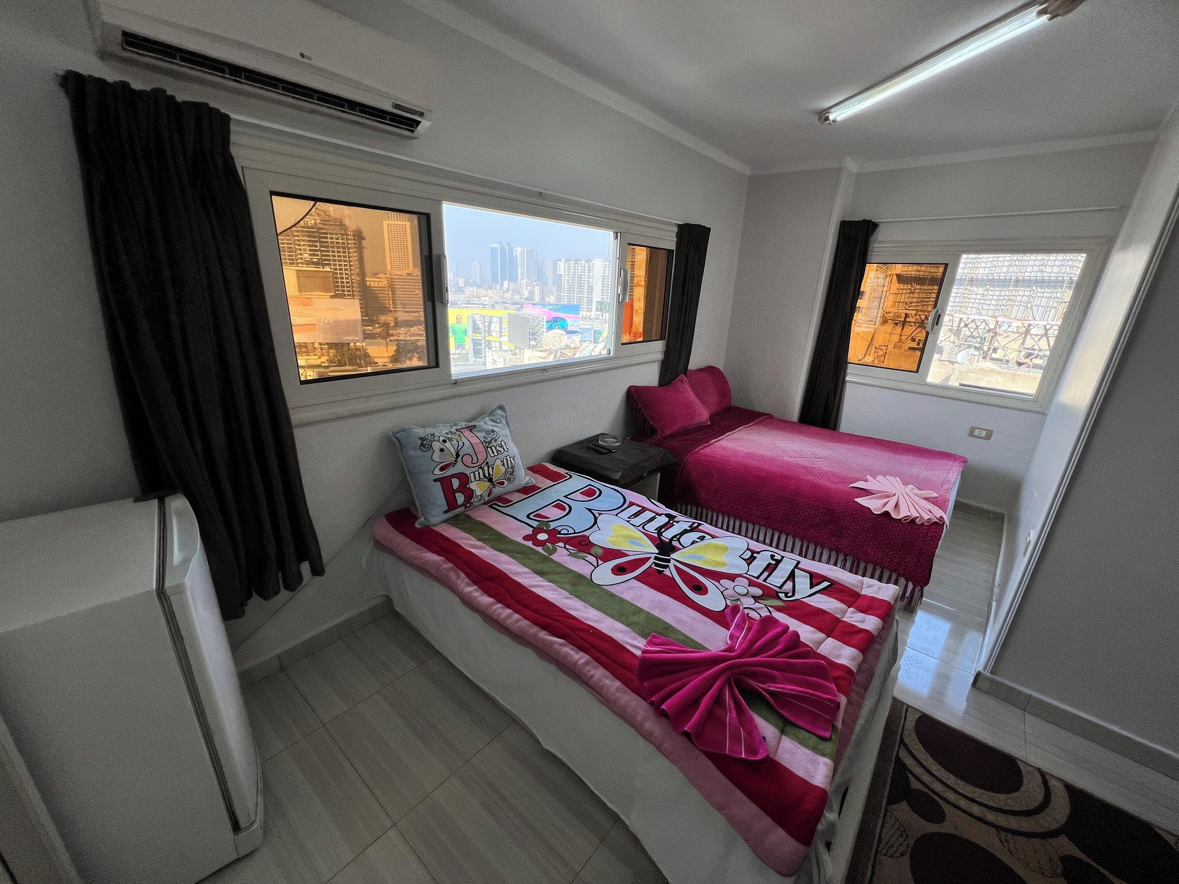 A compact room with a bunk bed, a small desk, and a window offering a city view.