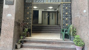 A hotel entrance with a staircase leading to the lobby, metal decorative panels, and potted plants. - Isis Hostel 2 (Cairo)