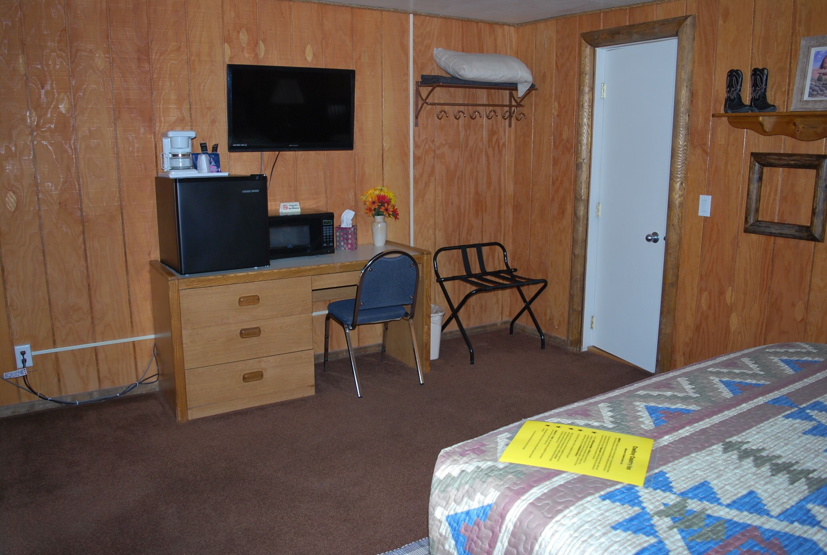 Une pièce comprenant un lit, un bureau avec un ordinateur, une chaise, un téléviseur et une porte.