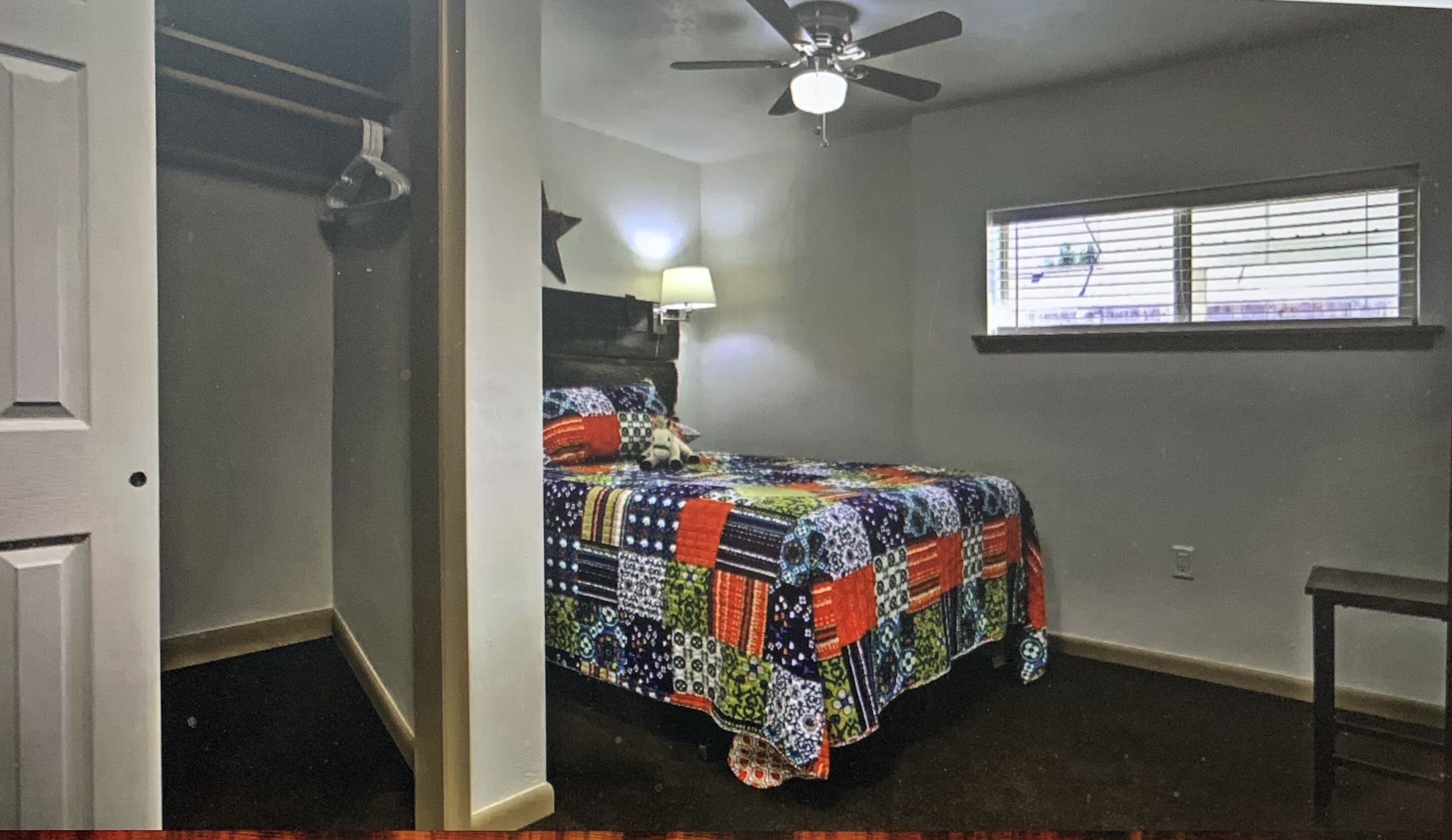 A bedroom with a bed, a ceiling fan, a window, and a door.