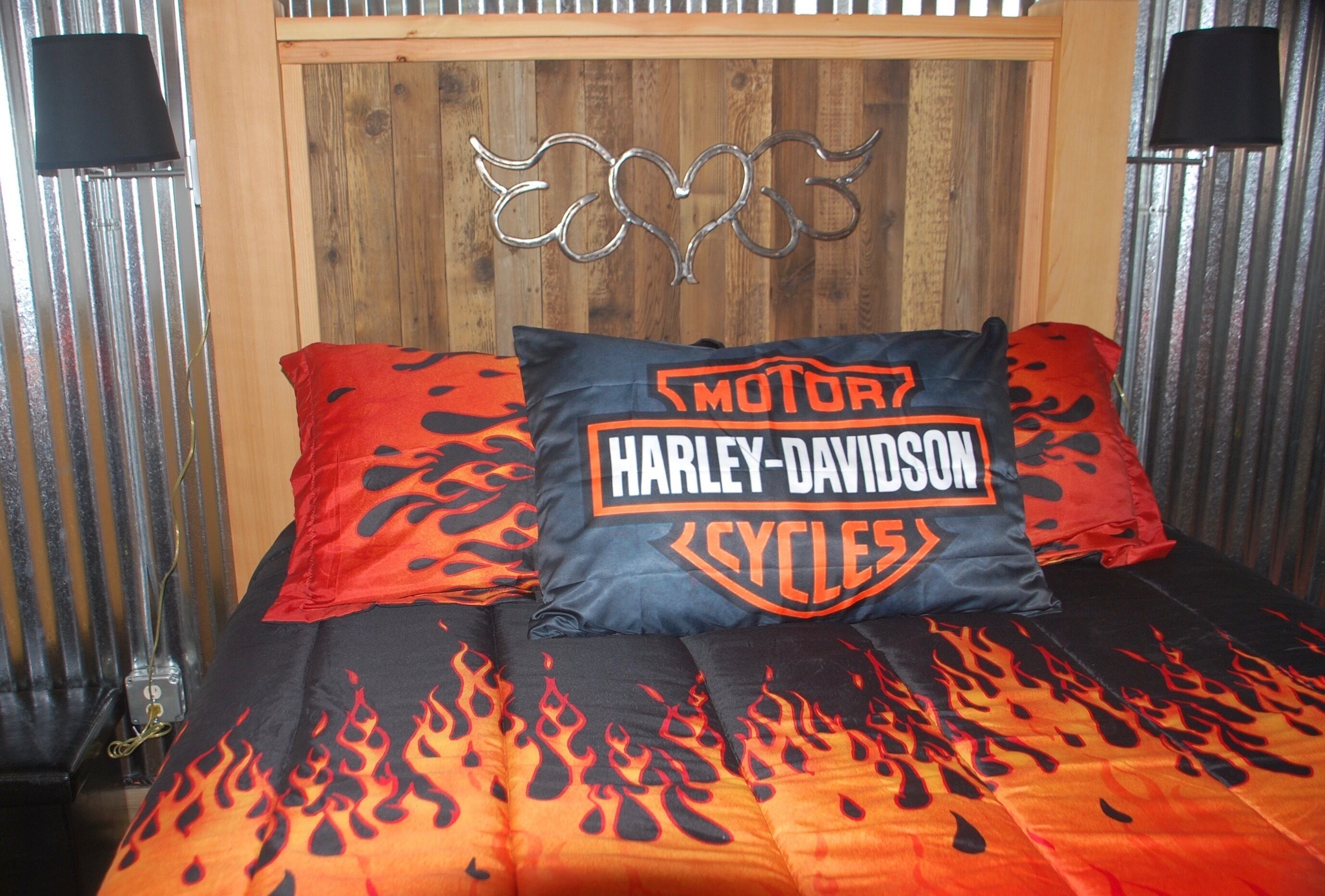 A bed with Harley-Davidson themed bedding, including a pillow and a blanket with flame designs.