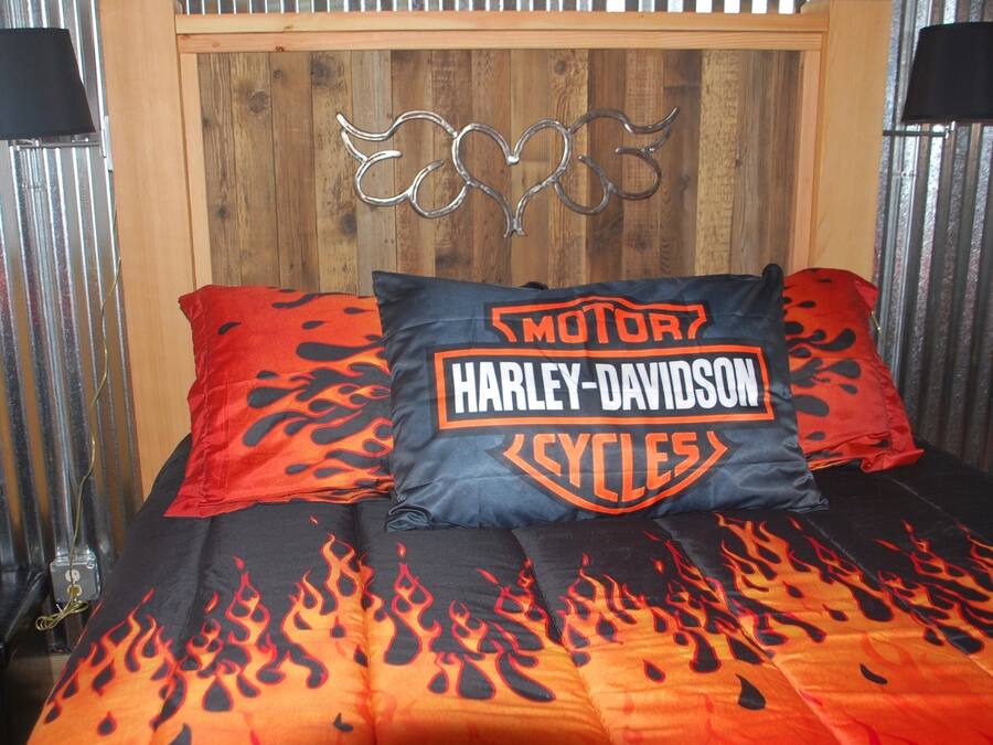 A bed with Harley-Davidson themed bedding, including a pillow and a blanket with flame designs.