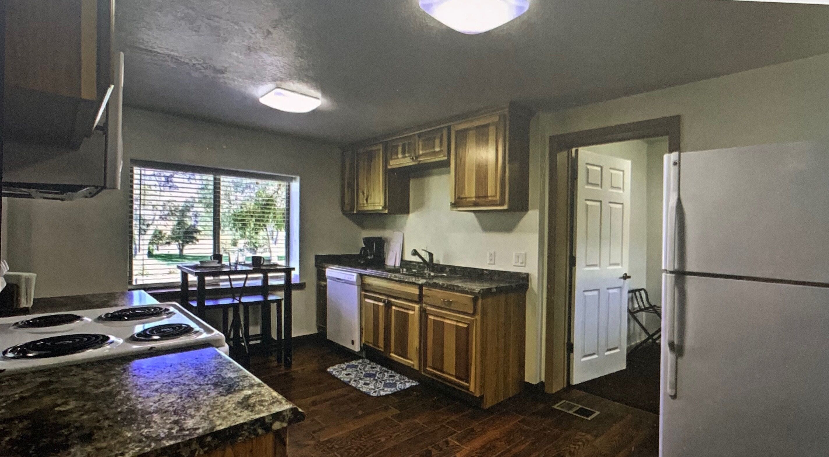 A kitchen with wooden cabinets, a stove, a sink, and a refrigerator.