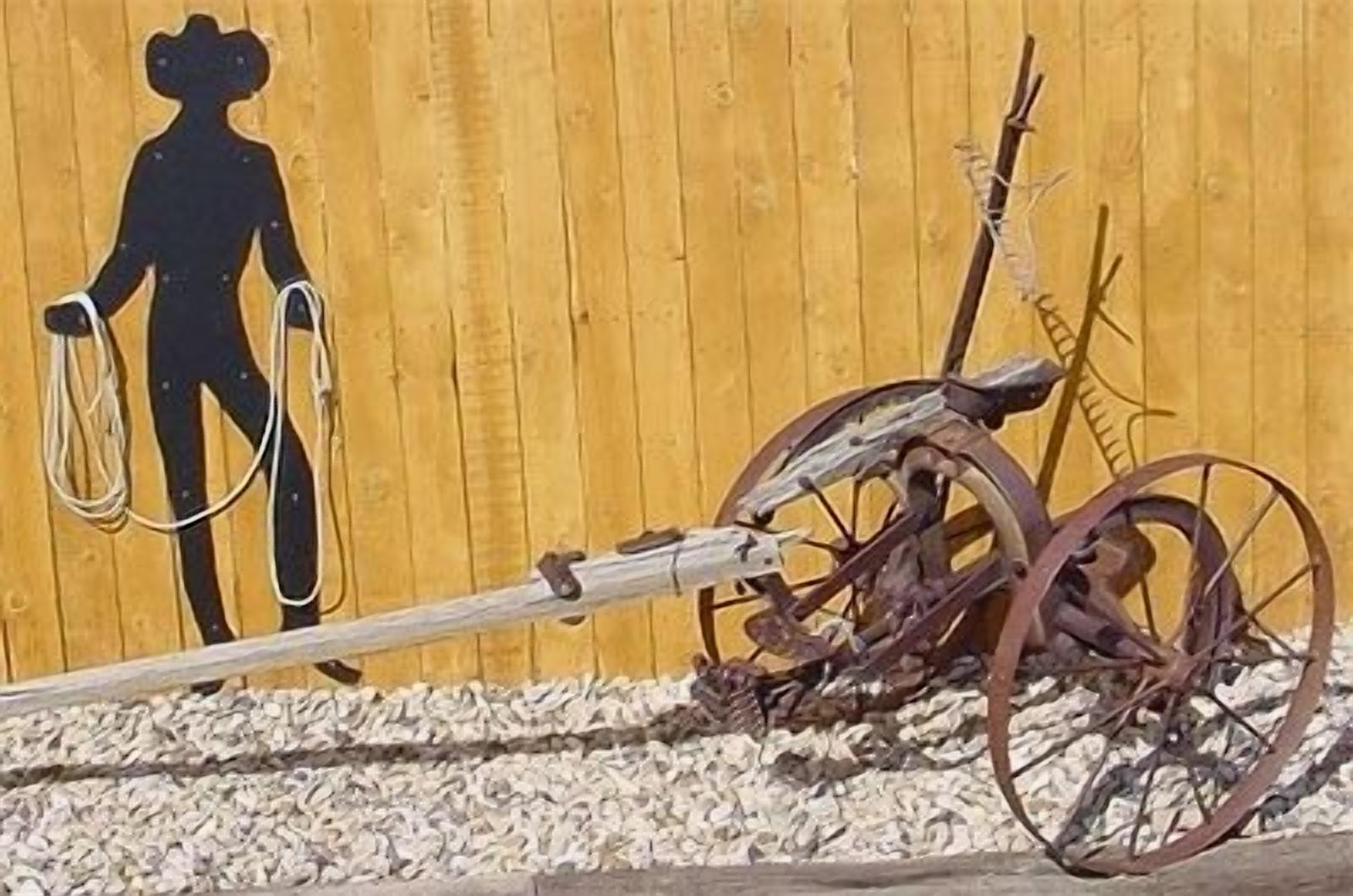 Ein rustikaler Holzzaun mit der Silhouette eines Cowboys, der ein Seil hält.