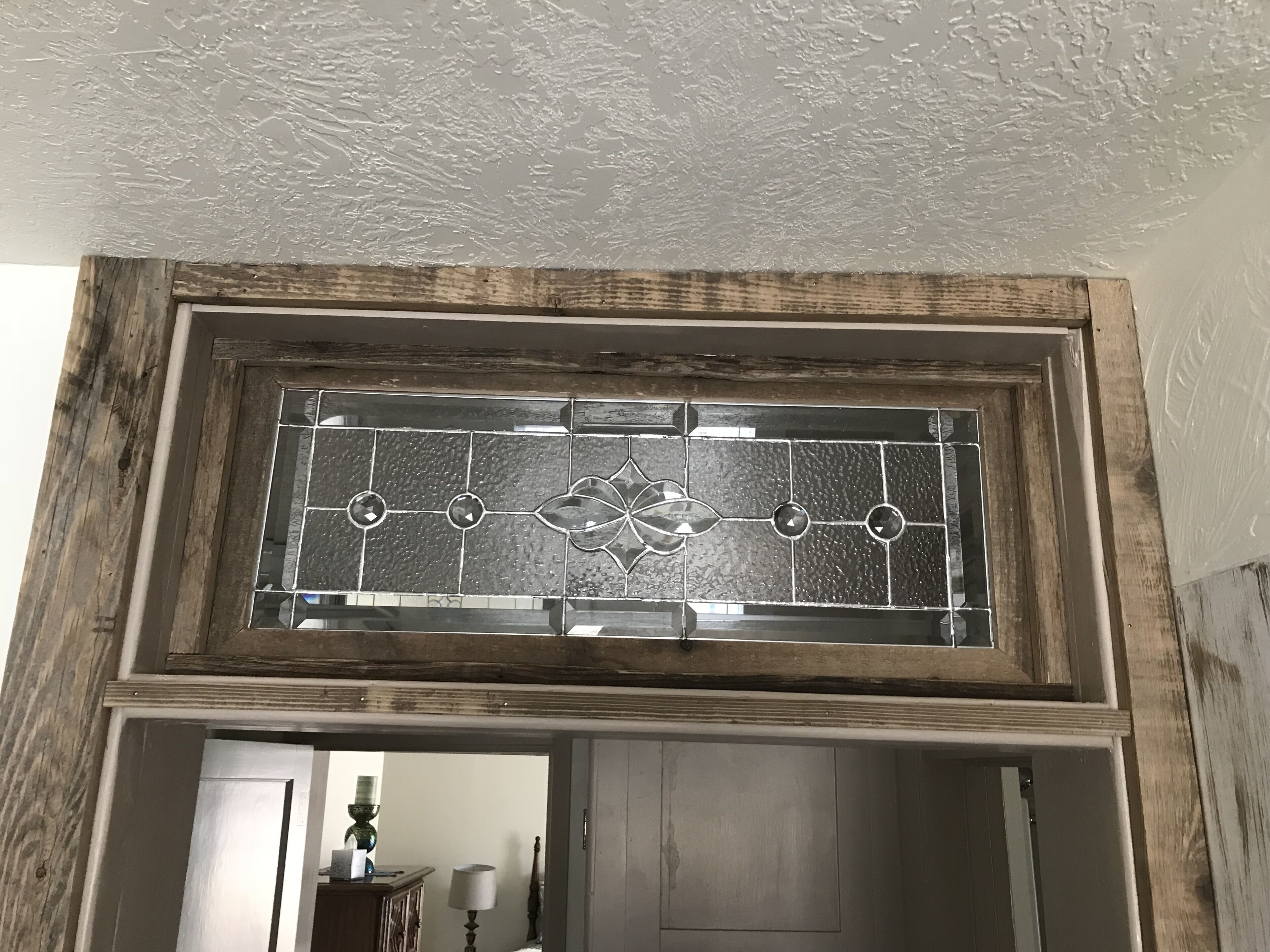 A rustic wooden-framed stained glass window with a geometric pattern.