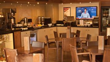 A restaurant with wooden furniture, a coffee bar, and a TV displaying the US Open.