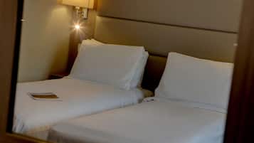 Una habitación de hotel con dos camas individuales, una mesita de noche y una lámpara.