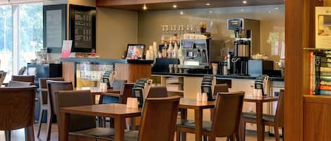 Una cafetería con mobiliario de madera, una máquina de café y una pizarra con el menú.