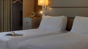A hotel room with two beds, a bedside table with a lamp, a bottle, and a glass. - Best Western Pontypool Metro Hotel (Pontypool)