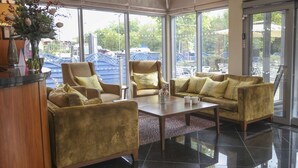 A spacious lobby with a large window offering a view of the outdoors, a reception desk, and seating arrangements. - Best Western Pontypool Metro Hotel (Pontypool)