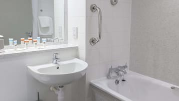 Une salle de bain moderne avec un lavabo blanc, une baignoire et une barre d’appui.