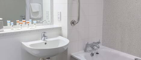 A modern bathroom with a white sink, a bathtub, and a handrail.