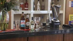 A bar counter with various bottles of alcohol, a glass, and a decorative item. - Best Western Pontypool Metro Hotel (Pontypool)