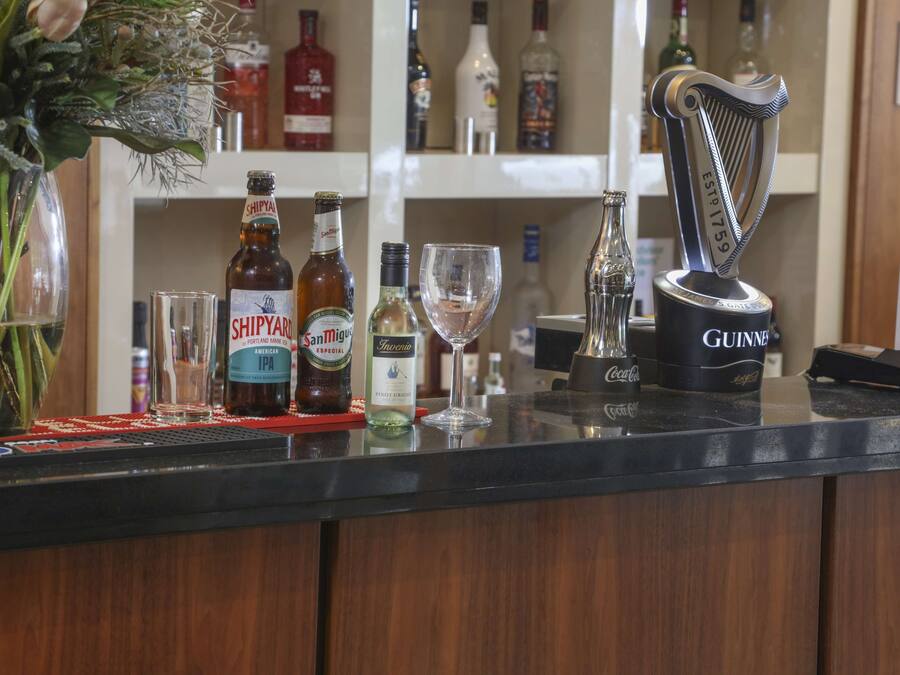 Una barra con varias botellas de alcohol, un vaso y un adorno.