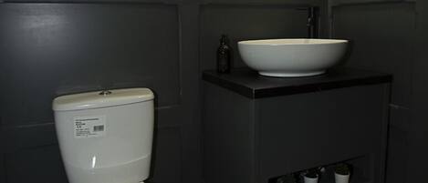 Een badkamer met toilet, wastafel, spiegel en een vloer met patroon.