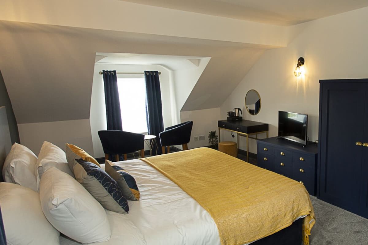 Ein Schlafzimmer mit einem Bett, einem Schreibtisch, einem Stuhl, einem Fernseher und einem Kleiderschrank.