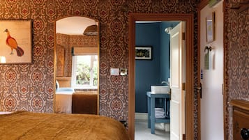 Un dormitorio con papel tapiz estampado, una cama, un espejo y vistas al baño.