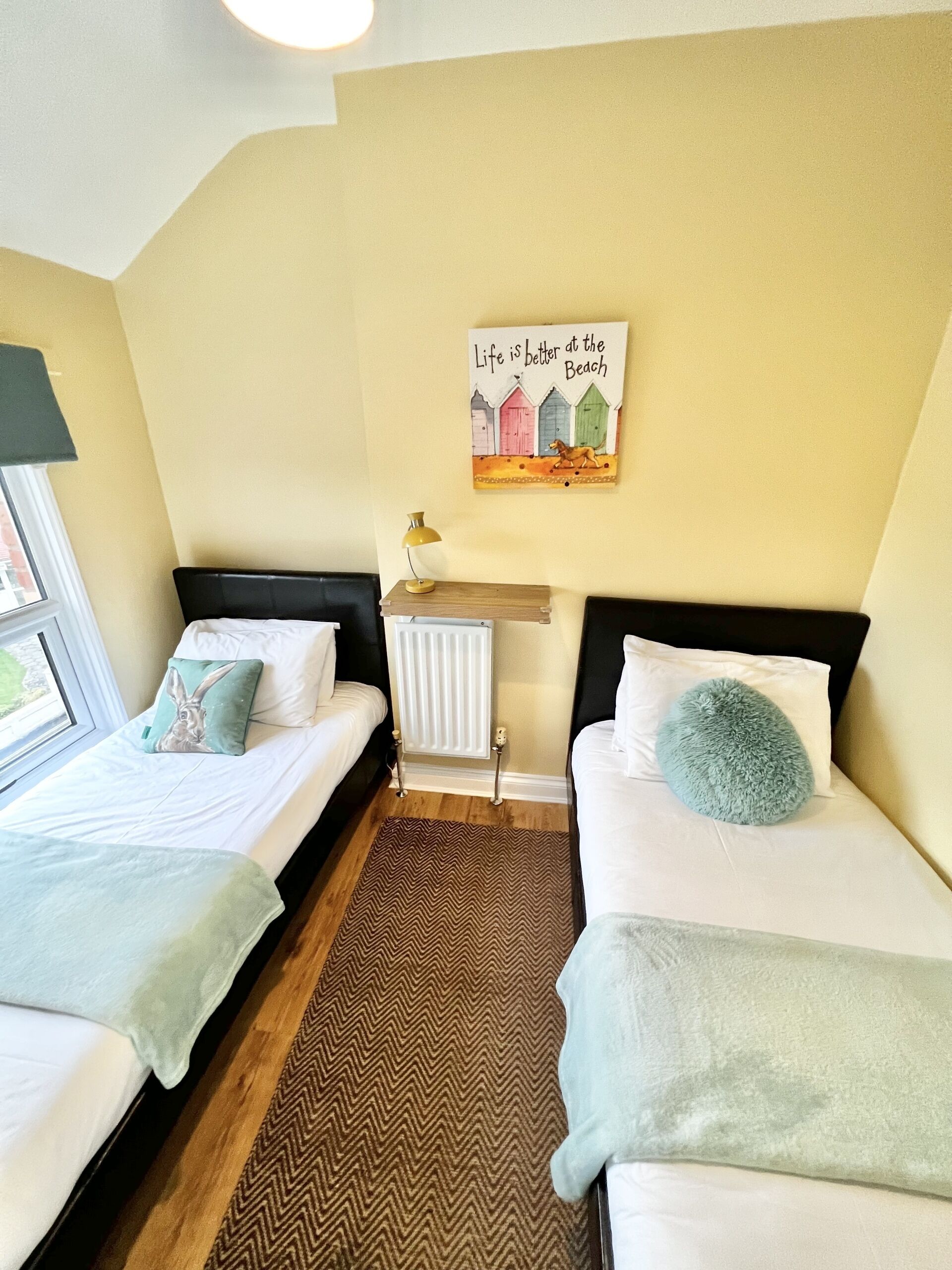 Een kamer met twee bedden, een radiator, een kunstwerk aan de muur en een raam.