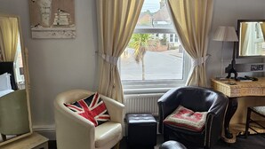 A hotel room with a bed, two chairs, a desk, a lamp, and a window with curtains. - Hooray Henrys Sheringham (Sheringham)