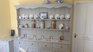 A kitchen with a white wooden cabinet displaying various dishes and jars. - Hooray Henrys Sheringham (Sheringham)