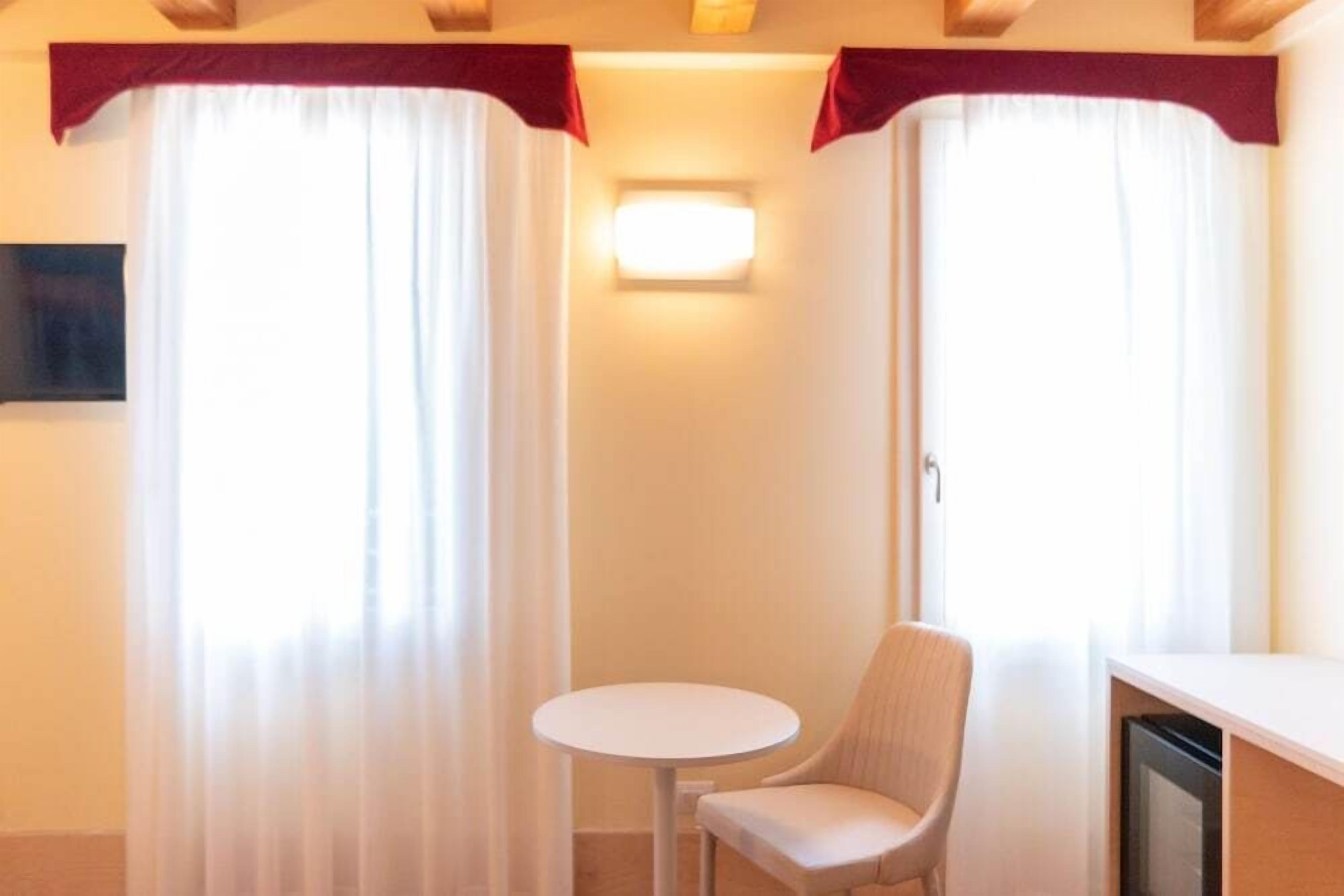 Una habitación con una mesa redonda, una silla y un televisor sobre un mueble.