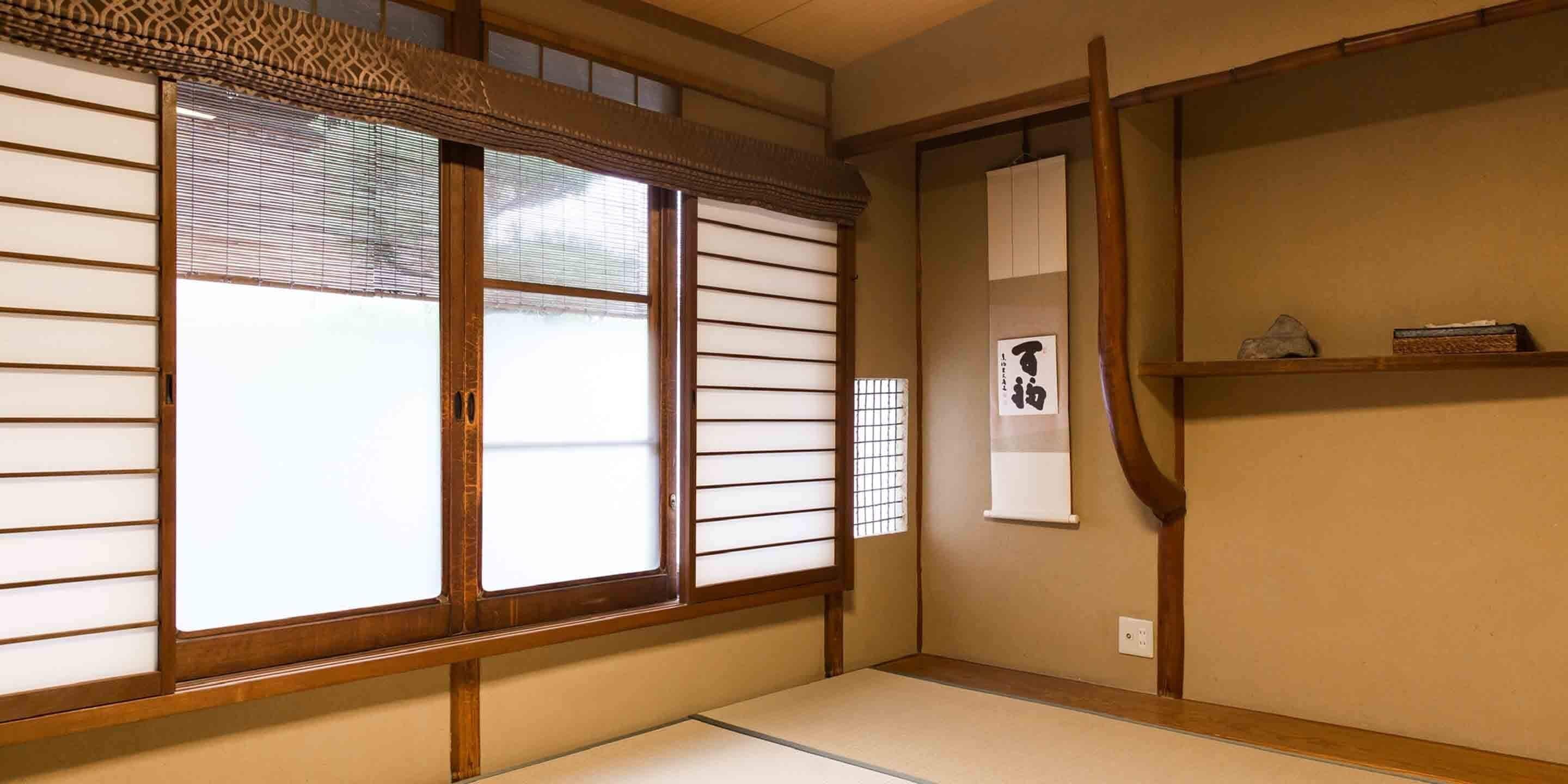 Ett traditionellt japanskt rum med tatamimattor på golvet, shojiskärmar och en skjutdörr.