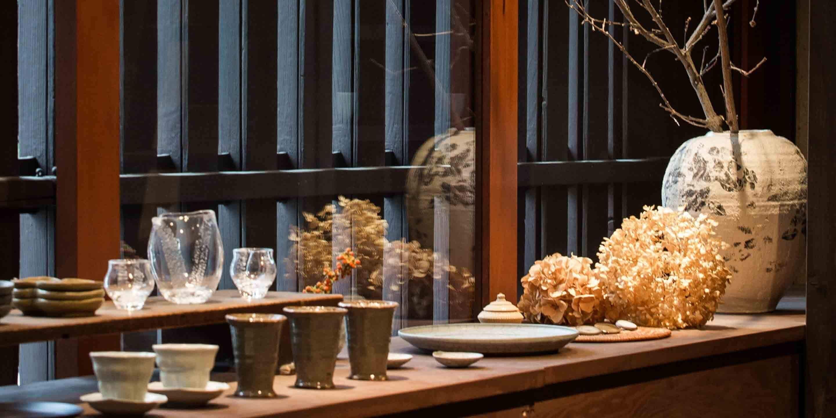 A wooden table with various ceramic items and dried flowers.