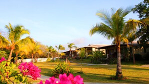 A tropical resort with palm trees, a pool, and a building with a tiled roof. - Playa Venao Hotel Resort (Las Escobas del Venado)