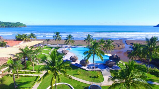 A resort with a swimming pool, palm trees, and a view of the beach and ocean. - Playa Venao Hotel Resort (Las Escobas del Venado)