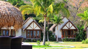 A resort with thatched-roof cottages, outdoor seating, and lush greenery. - Playa Venao Hotel Resort (Las Escobas del Venado)