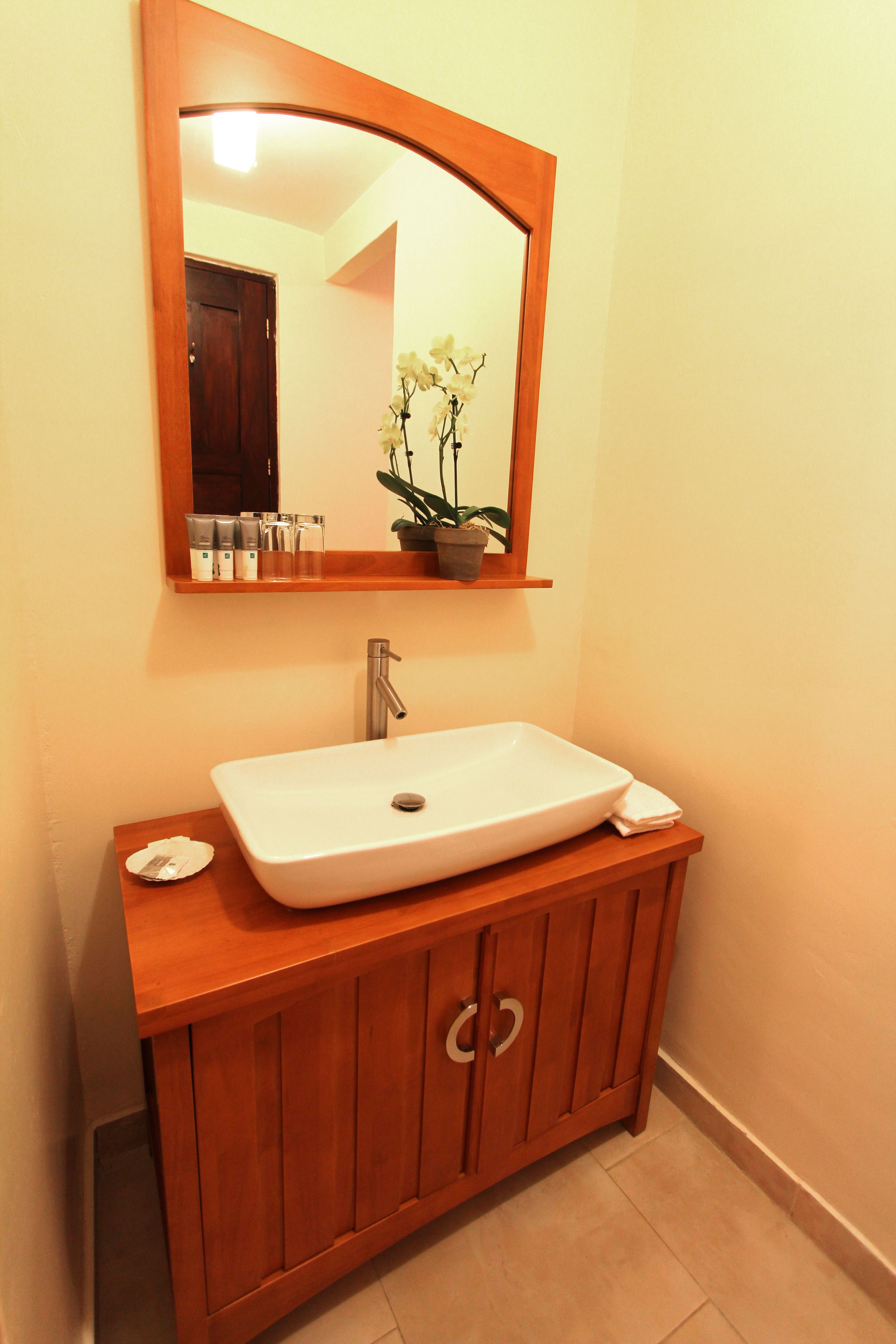 A bathroom with a white sink, wooden vanity, and a mirror above it.