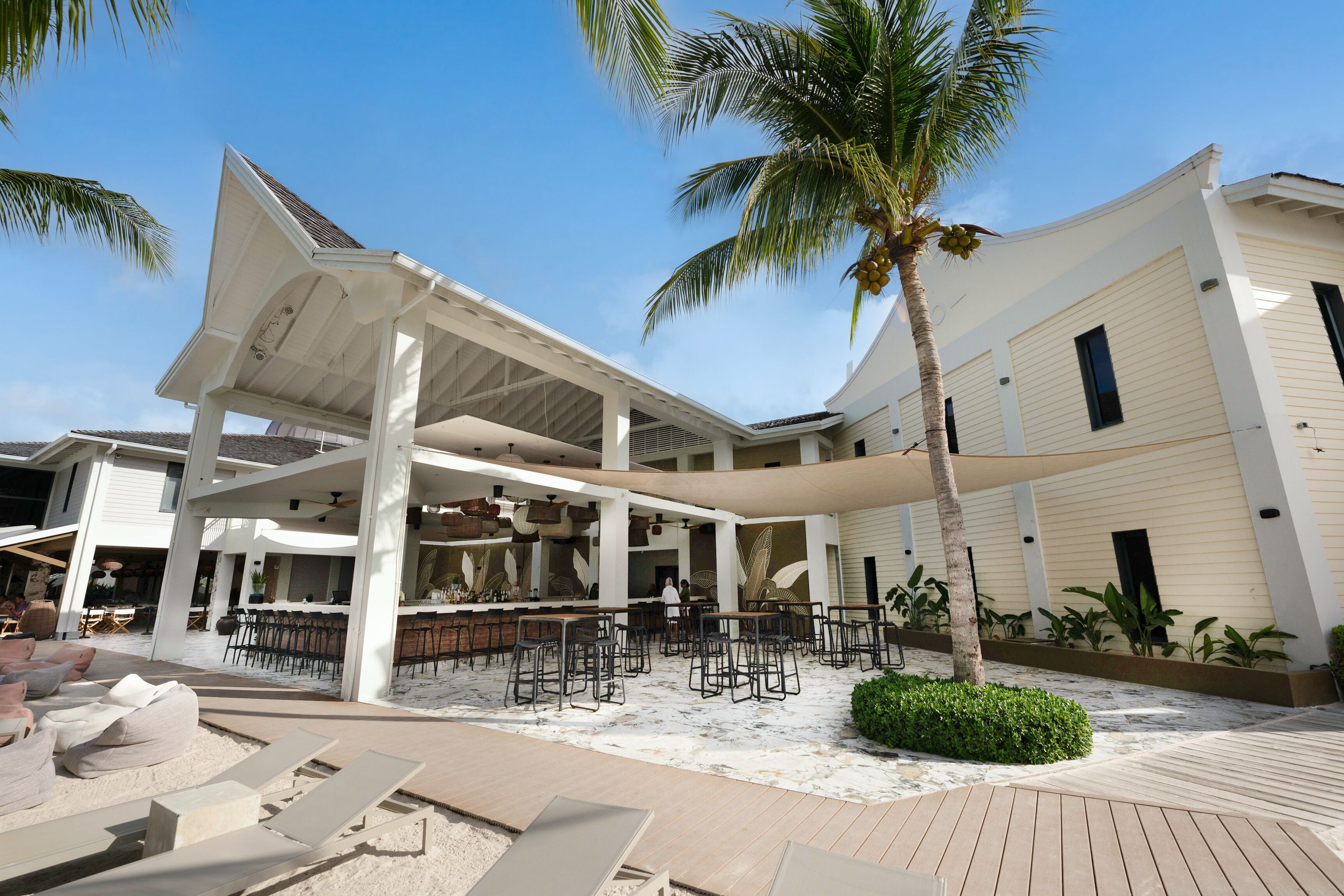 A resort with a covered outdoor seating area, a pool, and a bar/lounge area.