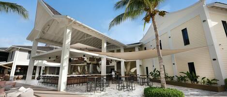 A resort with a covered outdoor seating area, a pool, and a bar/lounge area.
