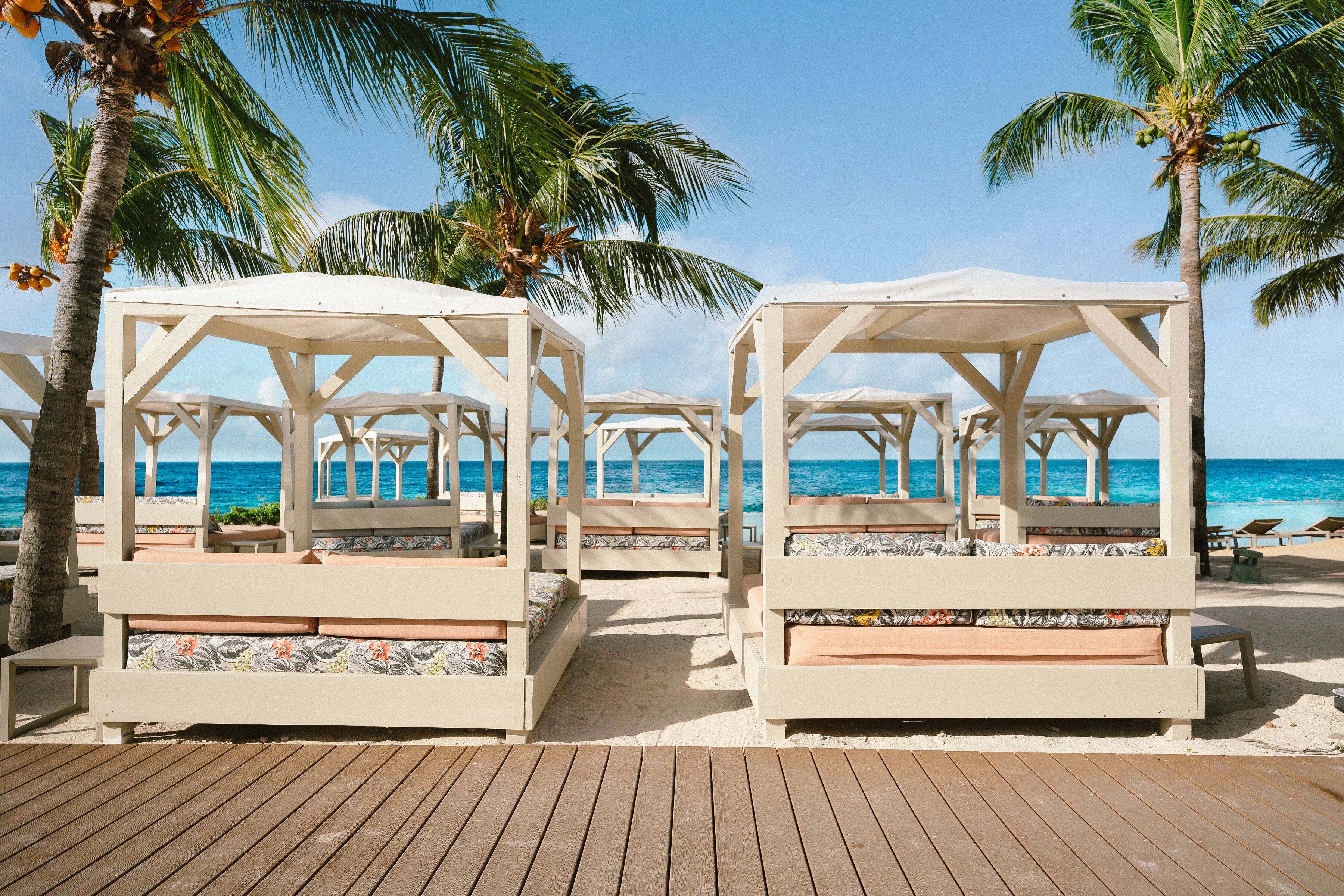 A beachside resort with wooden deck, palm trees, and beach chairs.