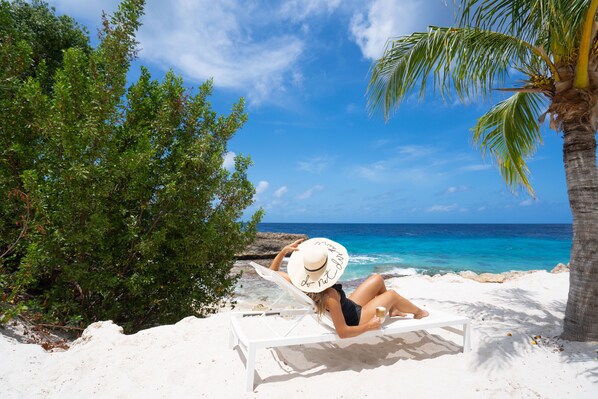 On the beach, white sand, sun loungers, beach towels