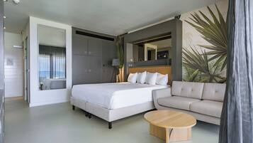 Una habitación de hotel moderna con una cama, un sofá, una mesita de café y un espejo grande.