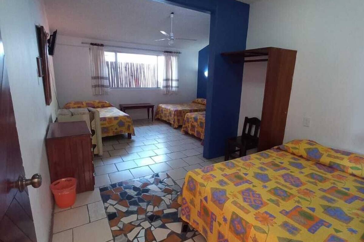 A hotel room with a bed, a desk, a chair, a small table, and a window with curtains.
