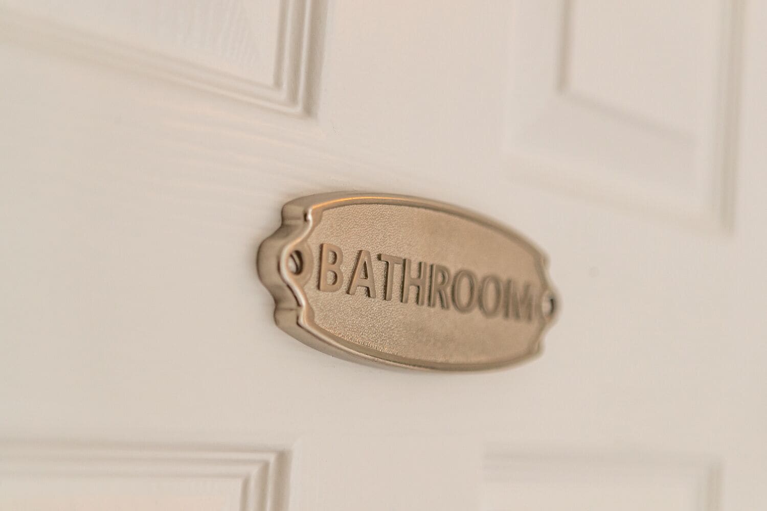 Une pancarte indiquant les toilettes sur une porte blanche.