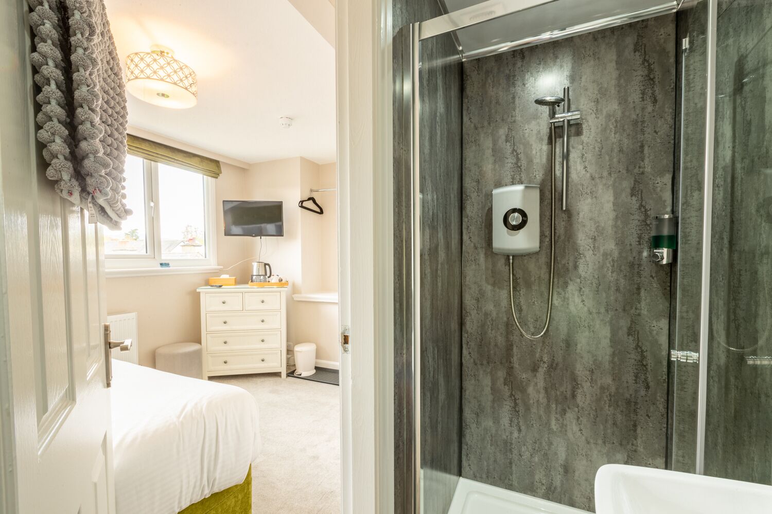 A modern bathroom with a glass-enclosed shower, a white sink, and a beige vanity.