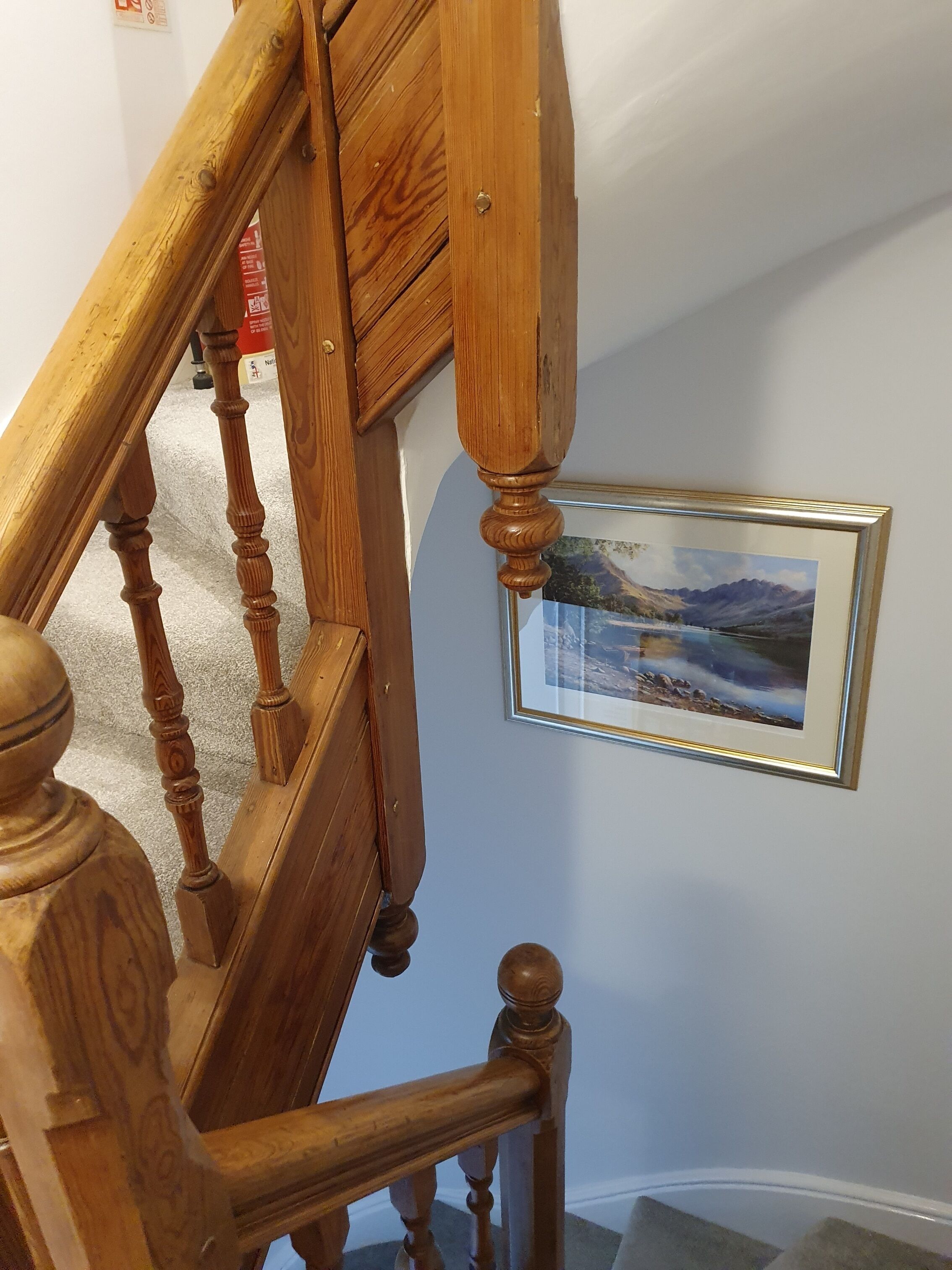 A wooden staircase with a framed landscape painting on the wall.