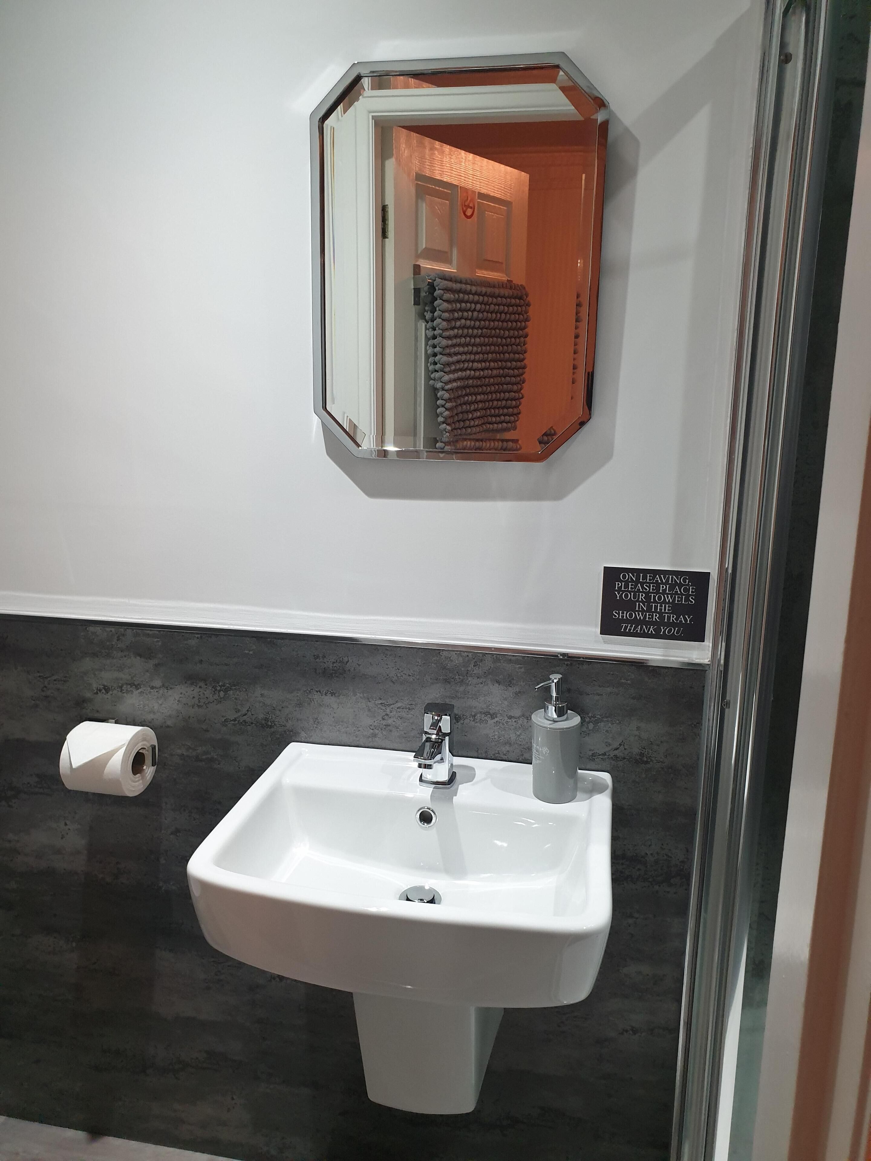 Une salle de bain avec un lavabo blanc, un distributeur de serviettes et un porte-rouleau de papier toilette.
