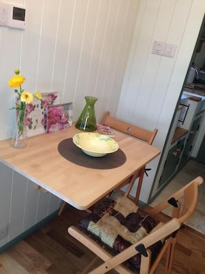 Un comedor con una mesa de madera, un tazón, un florero y una silla con cojín.