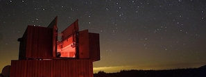 Una estructura de madera con un telescopio apuntando hacia el cielo nocturno.